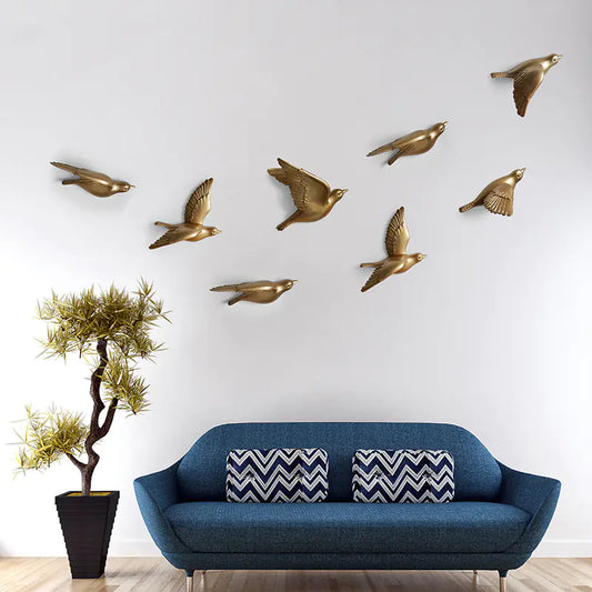 Blue sofa with decorative pillows in a room with gold bird wall art.