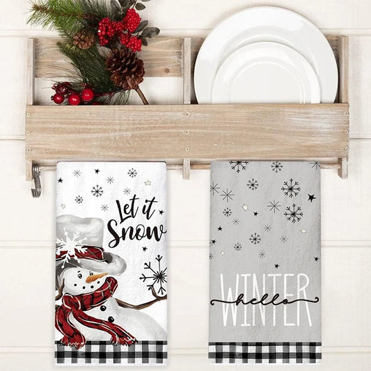 Decorative towel set with snowman design and 'Let it Snow' text, displayed on a wooden towel rack.
