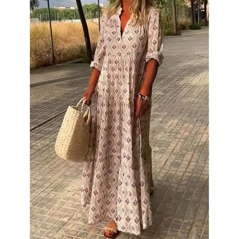 Woman in a long patterned dress holding a straw bag on a paved walkway.