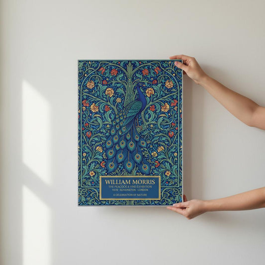 Vintage William Morris exhibition poster of a blue peacock with a long, detailed tail, surrounded by intricate green vines and orange flowers on a dark teal background. Cream-colored text at the bottom reads William Morris The Peacock and Vine Exhibition.