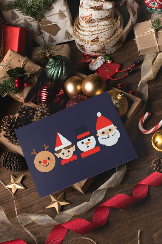 Navy blue card with festive characters surrounded by Christmas decorations on a wooden surface