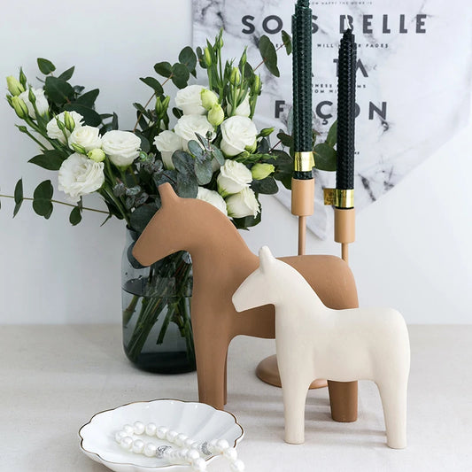 Decorative horse figures with a vase of flowers and makeup brushes on a marble surface.