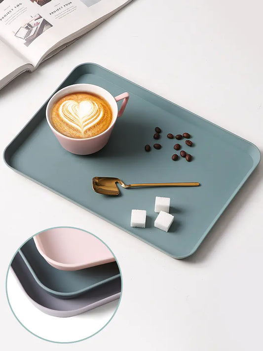 Teal tray with a cup of coffee, coffee beans, and a spoon on a white surface.