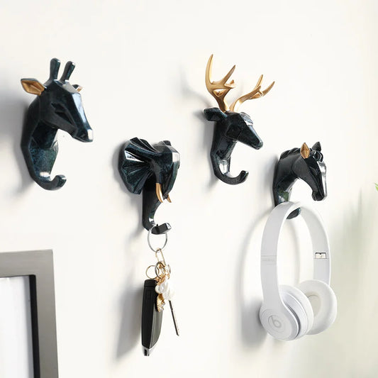 Wall hooks shaped like animal heads with a pair of white headphones hanging on one of them.
