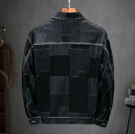 Black denim jacket with patchwork design on a gray background