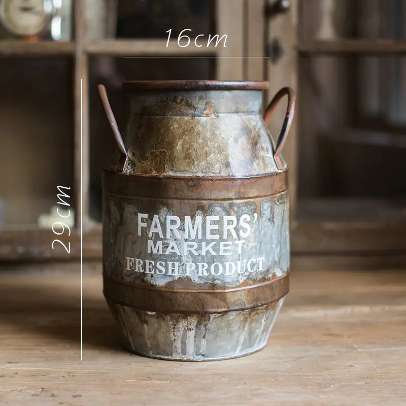 Vintage-style metal milk churn with 'Farmers' Market Fresh Product' text on a wooden surface.