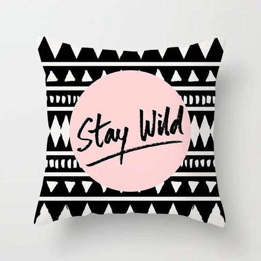 Decorative pillow with black and white tribal pattern and pink circle with 'Stay Wild' text on a light gray background