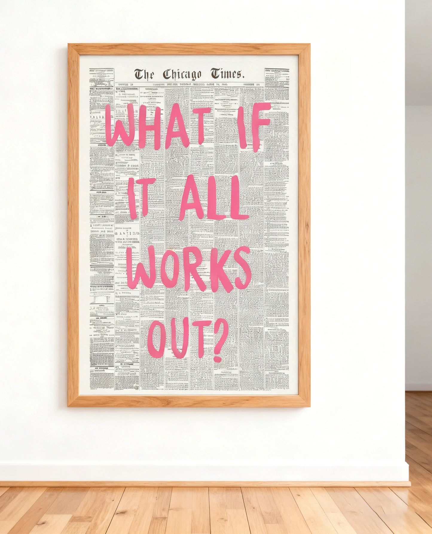 Framed newspaper with 'What If It All Works Out?' text in pink on a white wall.