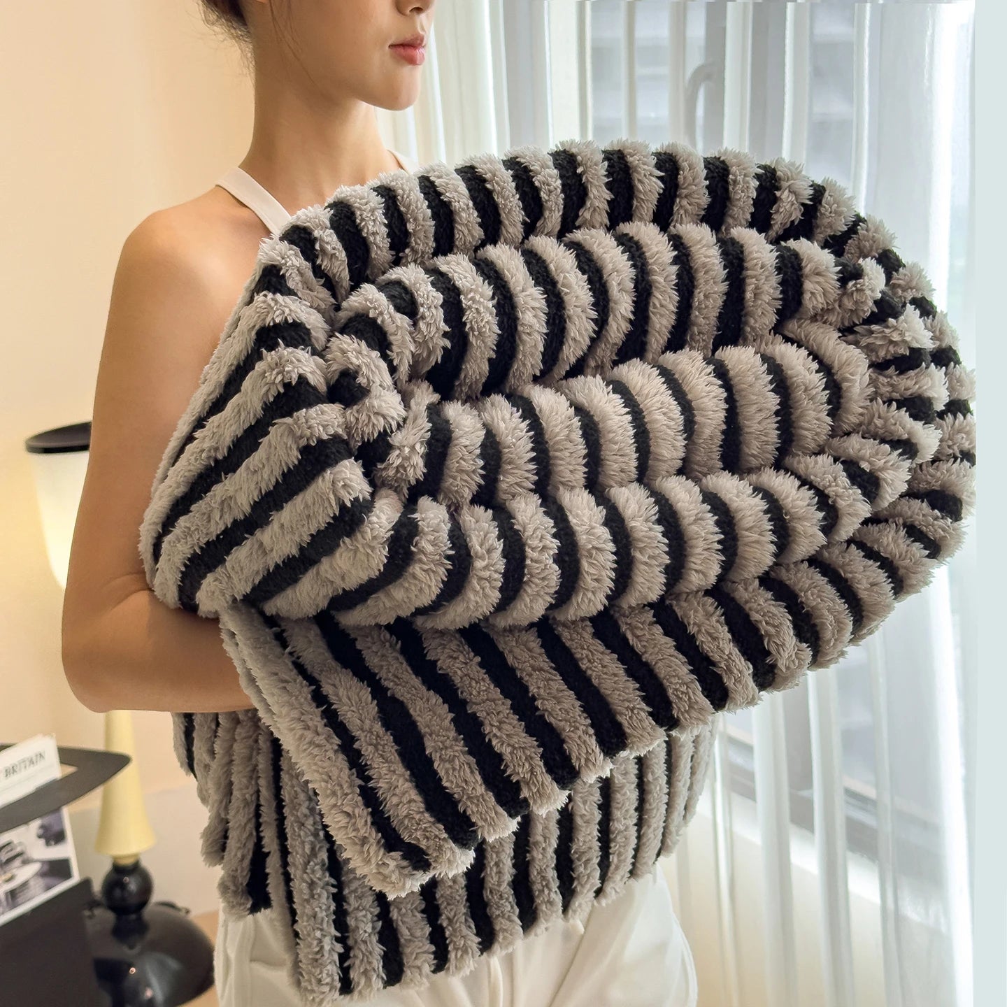 Person holding a striped, fluffy blanket indoors