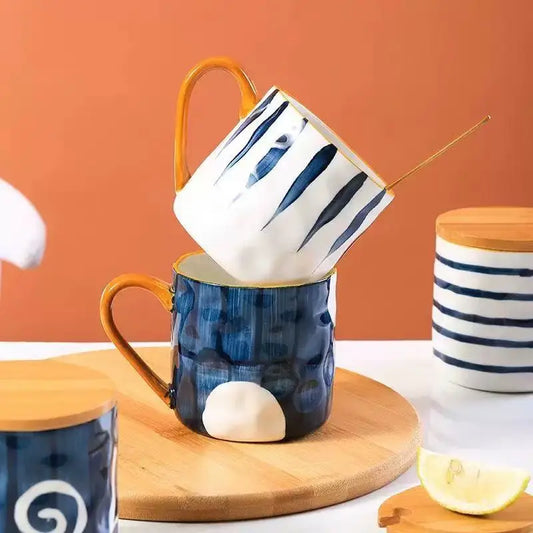 Two ceramic mugs, one blue with a white interior and the other white with black stripes, on a wooden cutting board against an orange background.