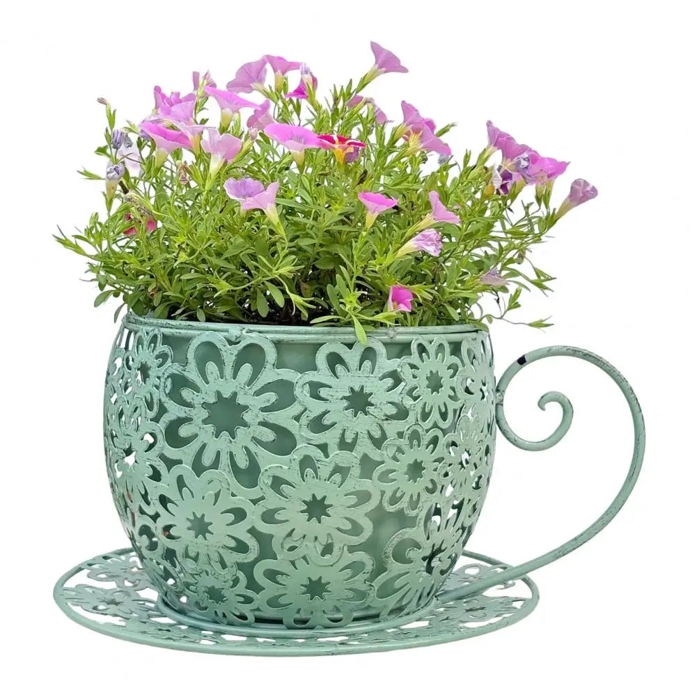 Decorative metal cup with floral pattern containing pink flowers on a white background