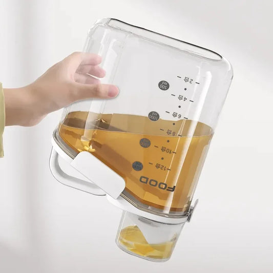 Clear glass pitcher with handle filled with liquid, held by a hand on a white background