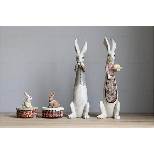 Set of decorative rabbit figurines on a wooden surface with a gray background
