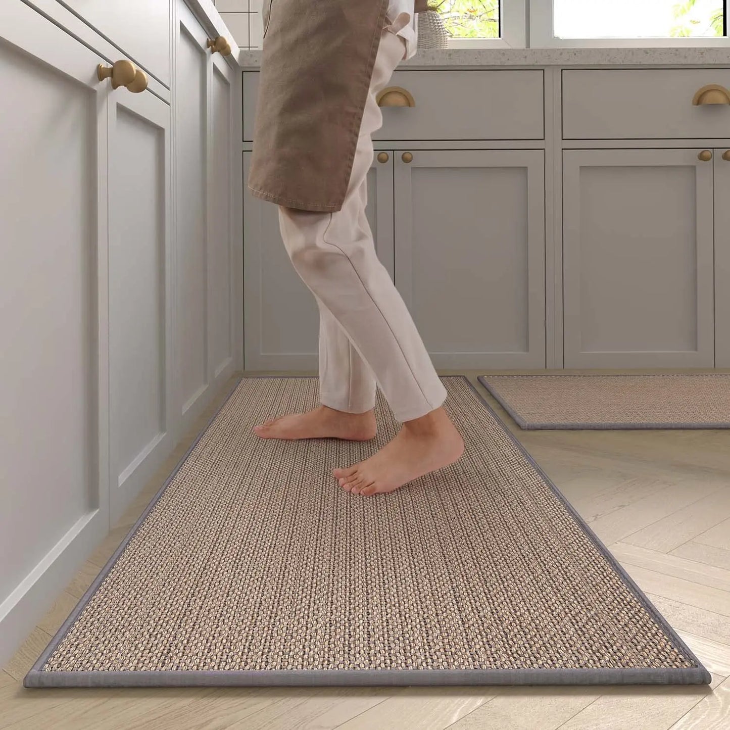 Person walking on a textured rug in a kitchen with gray cabinets.