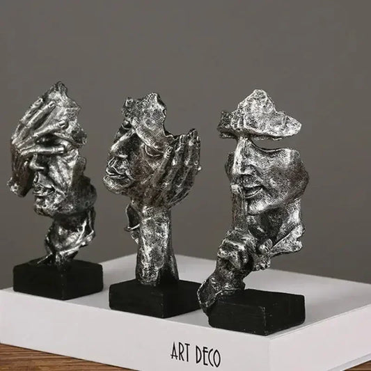 Three Art Deco-style Silver sculptures on a white base with a gray background on a white surface