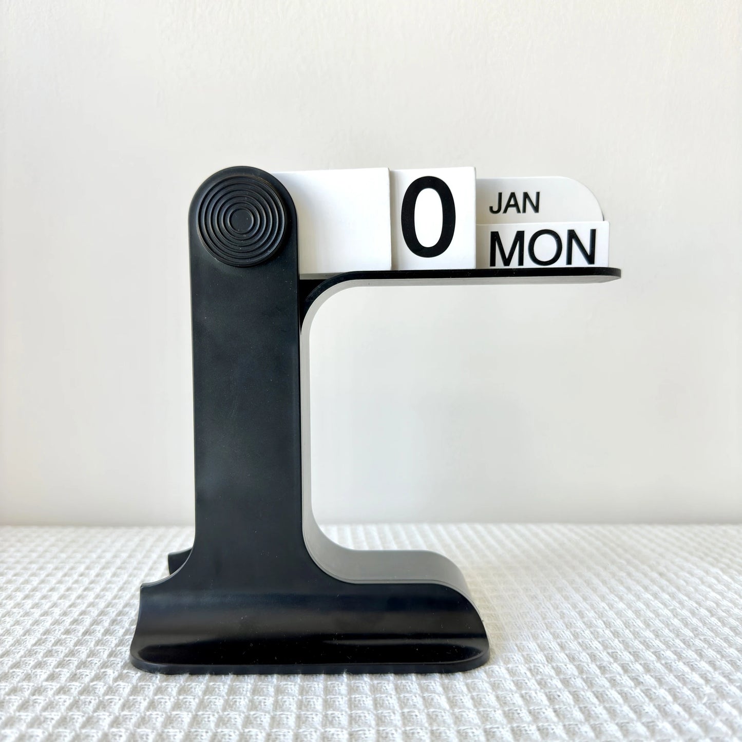 Black and white calendar stand on a textured surface with a light background