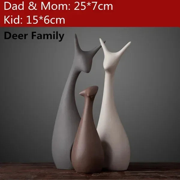 Three deer figurines of different sizes on a wooden surface with a gray background.