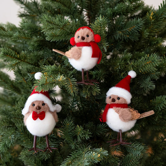 Three festive bird ornaments in red and white hats on a Christmas tree.