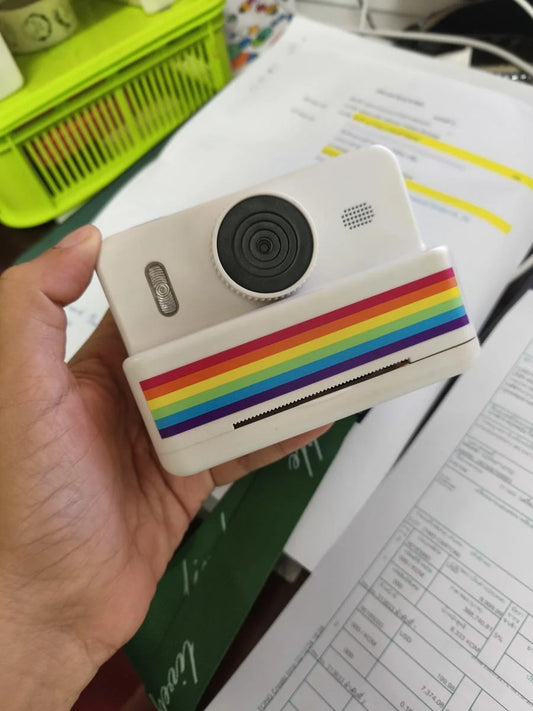 Hand holding a device with a rainbow case on a desk with papers and stationery.