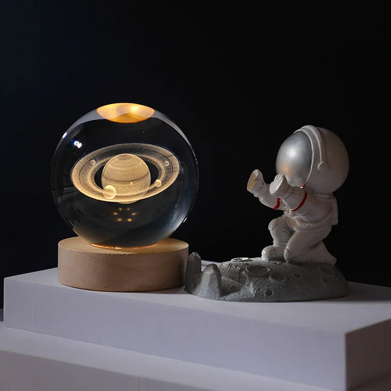 Glass sphere with Saturn model and astronaut figurine on a dark background