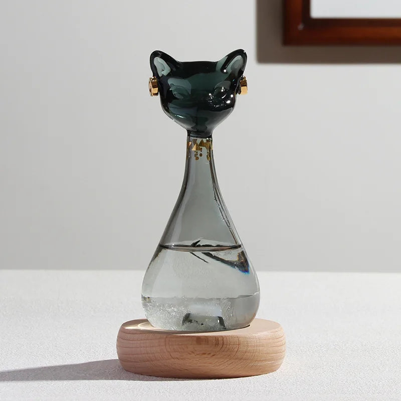 Glass bottle with cat-shaped top on a wooden base against a plain background