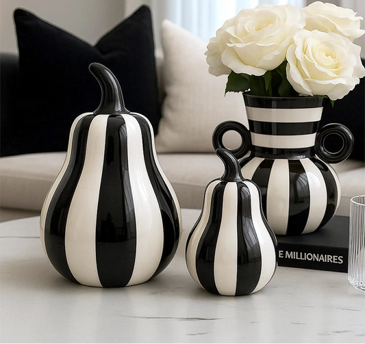 Black and white striped vases on a table with a vase of white roses in the background.