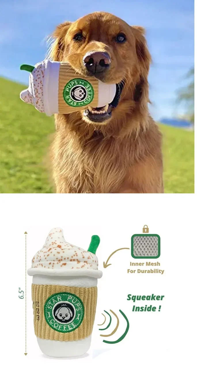 Dog holding a toy shaped like a coffee cup with a visible brand logo, set against a grassy outdoor background.