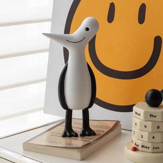 Decorative penguin figure on a book with a smiley face poster in the background