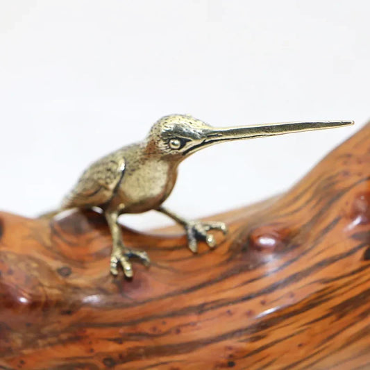 Bronze bird figurine on a wooden surface with a white background