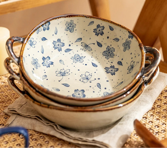 Stack of ceramic bowls with floral pattern on a woven surface