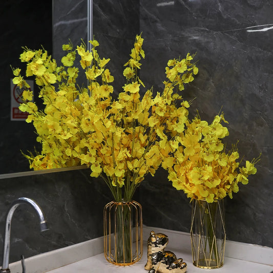 Two vases with yellow flowers on a dark marble countertop.