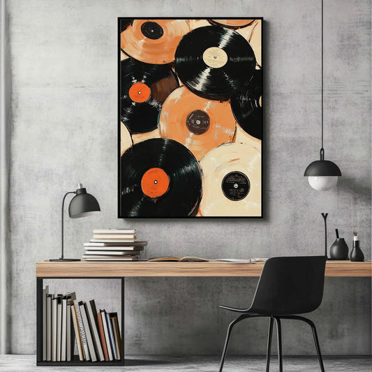 Framed artwork of vinyl records on a wall above a desk with books and a chair.