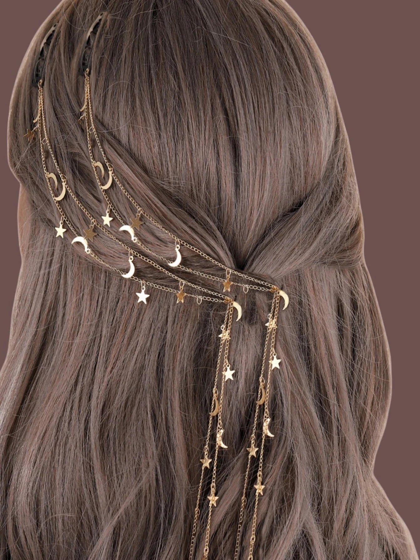 Hair accessory with gold chain, stars, and moons on brown hair against a brown background