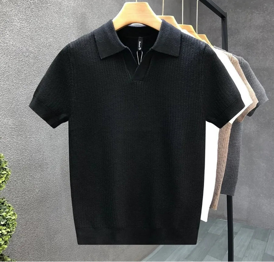 Black polo shirt on a hanger against a gray wall