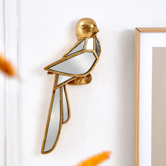 Gold bird-shaped mirror on a white wall