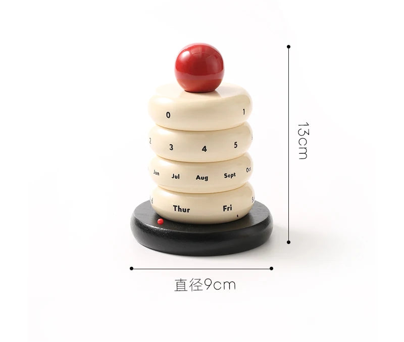 Colorful rotating cake calendar on a white surface with a blurred background showing measurements