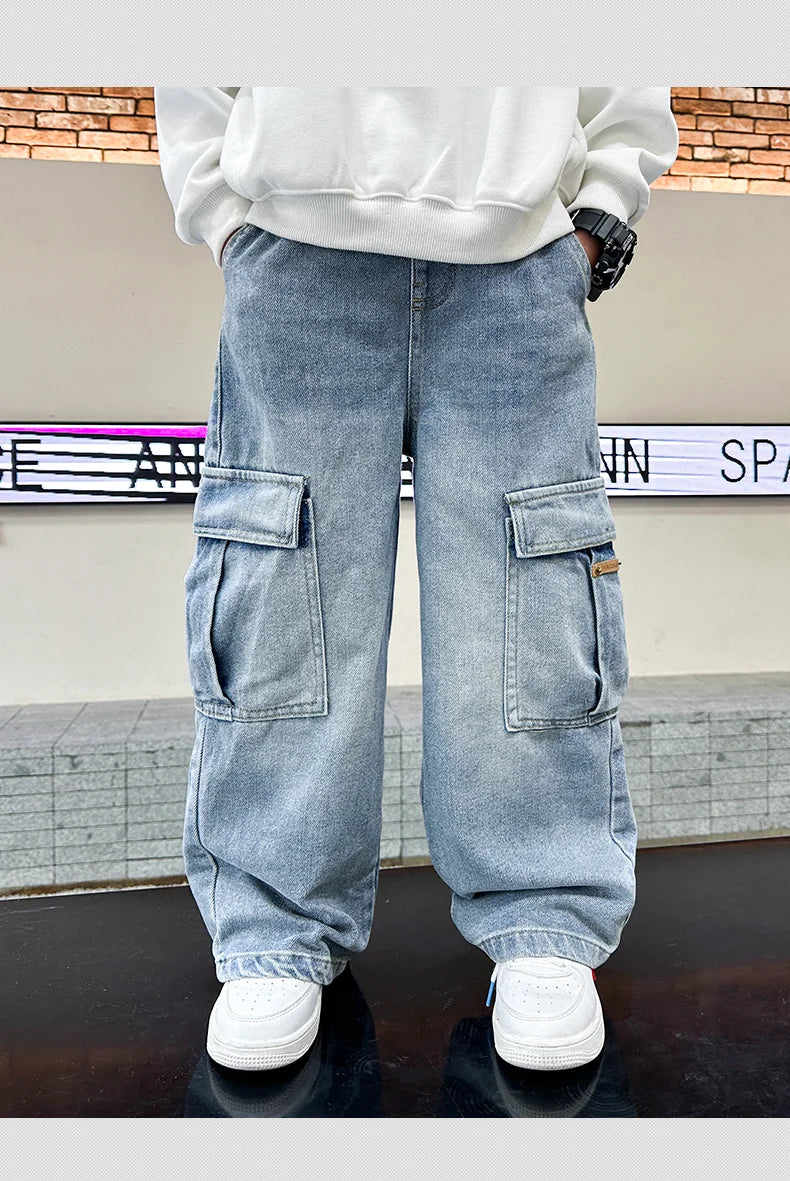 Person wearing light blue cargo pants with a white sweatshirt and white shoes in front of a brick wall.