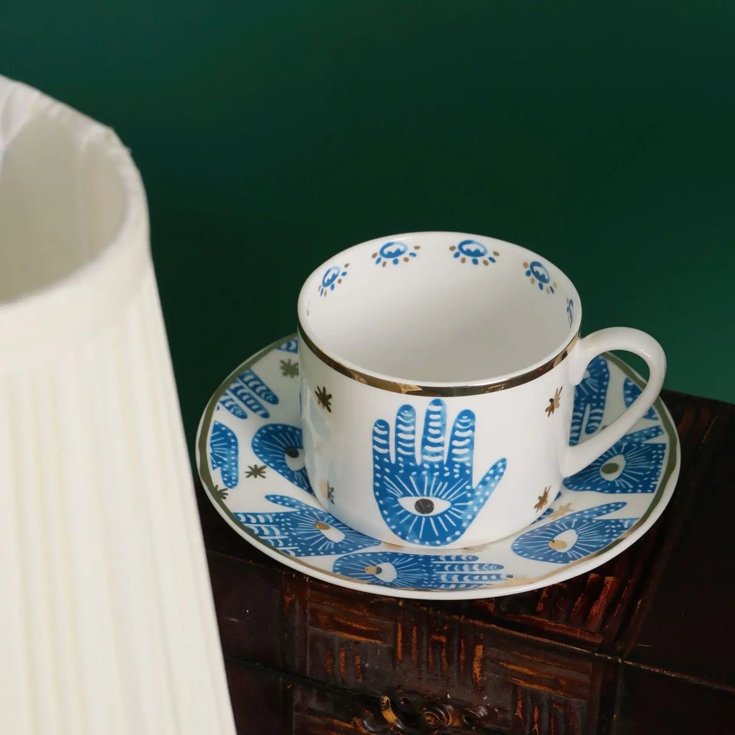 Ceramic cup and saucer with blue hand design on a wooden surface