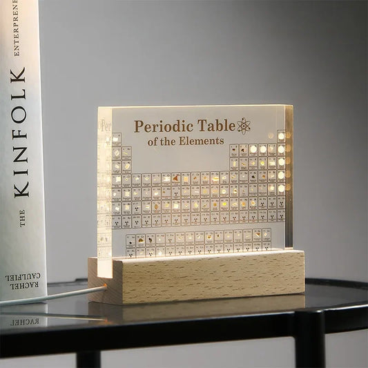 Luminous periodic table of elements on a wooden base with a book in the background