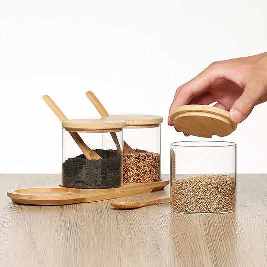 Glass jars with wooden lids and spoons on a wooden surface