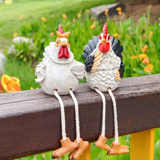 Two decorative rooster figurines on a wooden surface with a garden background.