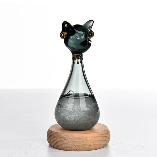 Black and white Egyptian-inspired cat storm glasses with gold-coloured details and visible crystals, displayed on round wooden bases.
