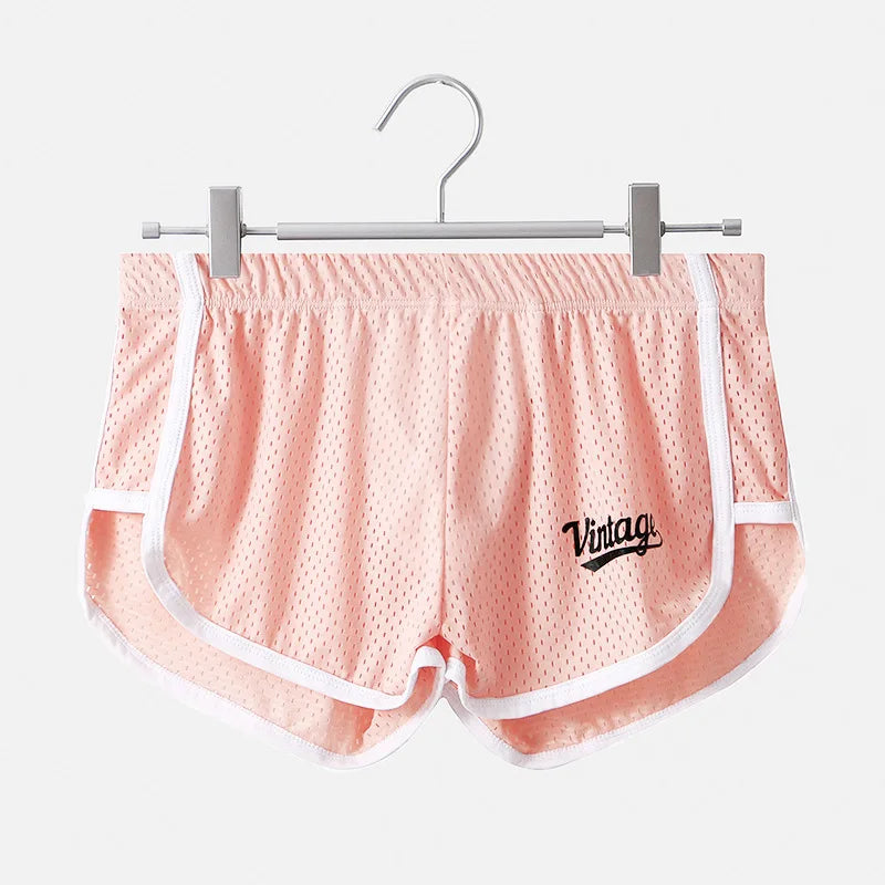 Pink mesh shorts with white trim and 'Vintage' logo on a hanger against a white background