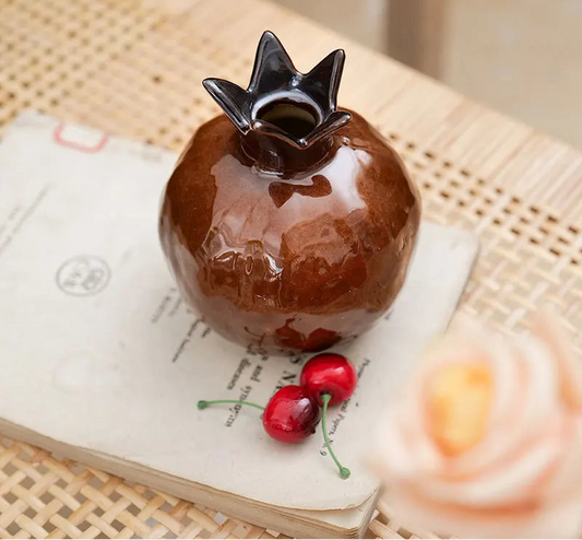Ceramic pomegranate vase ornament with glossy glazed finish used as decorative tabletop décor close up view