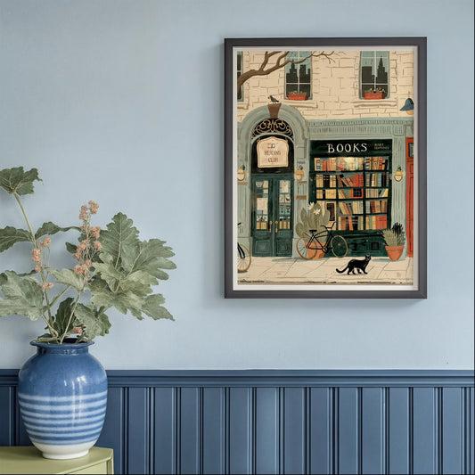 Framed artwork of a bookstore scene on a wall with a plant and vase below.
