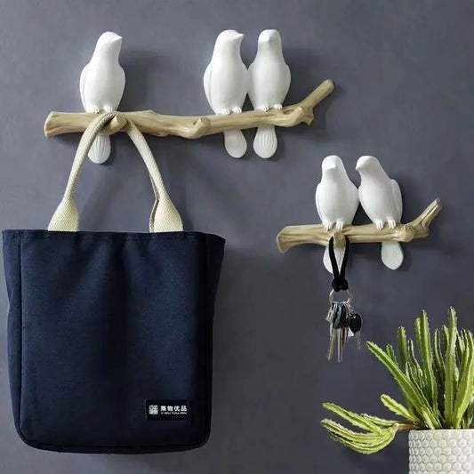 Wall hooks shaped like birds with a black bag and keys on a gray background