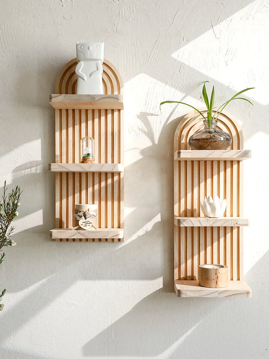 Two wooden wall shelves with decorative items against a white wall.