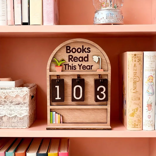 Wooden bookshelf with a decorative item showing '103 Books Read This Year' on a pink shelf.