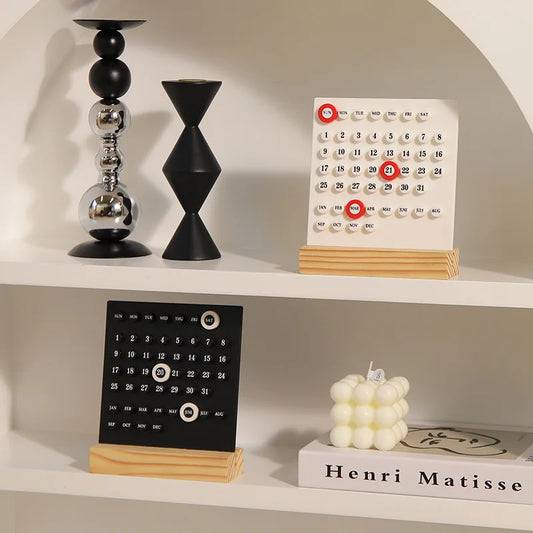 Two desk calendars on a shelf with decorative items