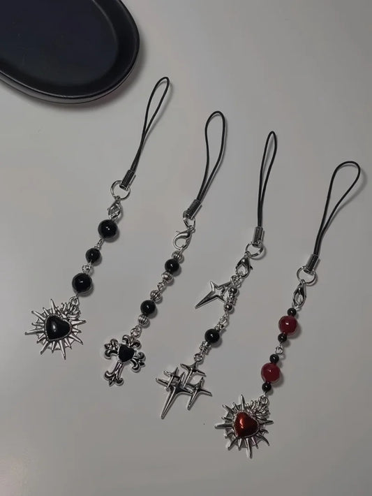 Four decorative phone straps with star and cross designs on a white surface.